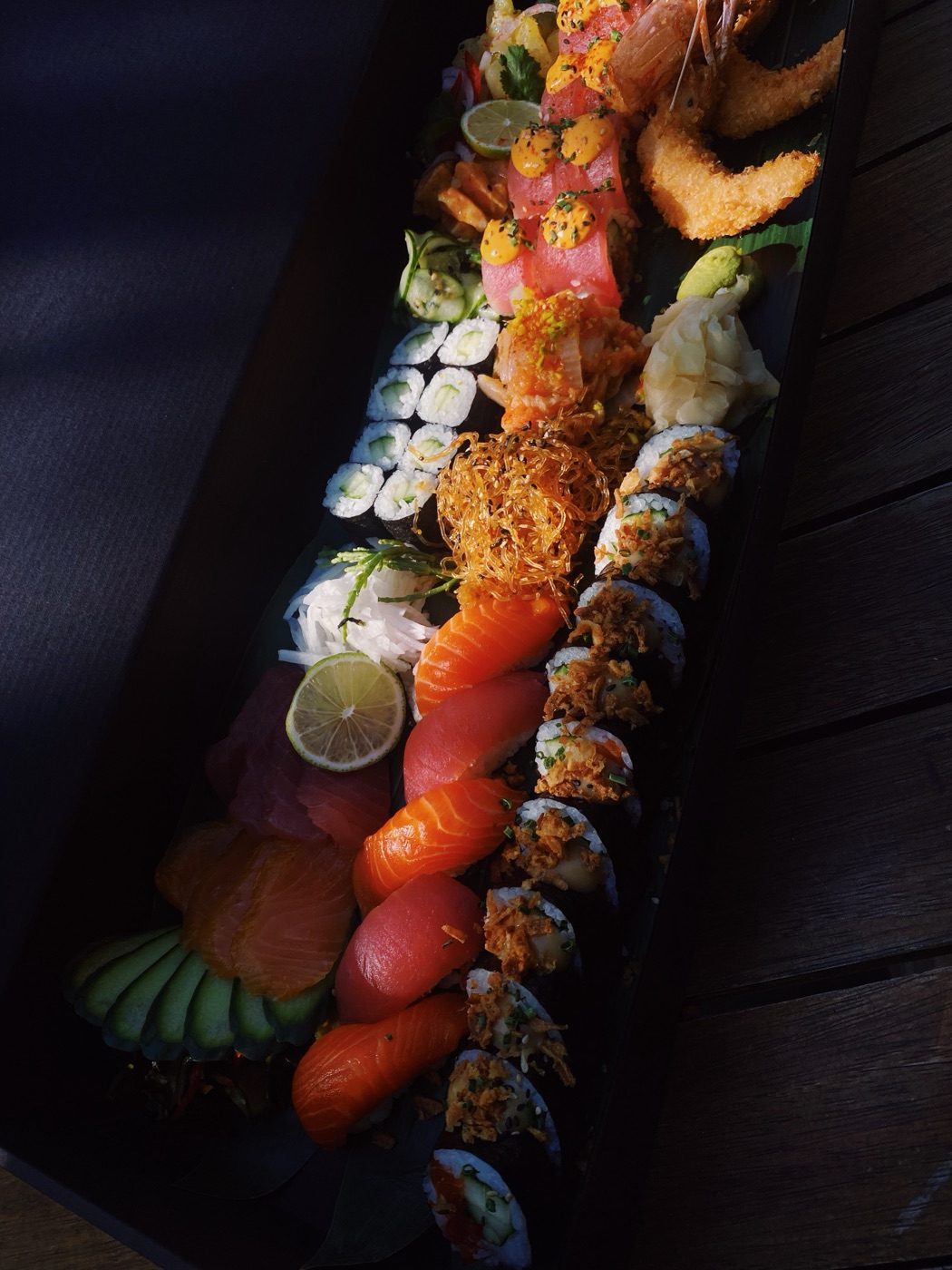 Lange schwarze Sushi-Platte mit Nigiri, Sashimi und Rolls